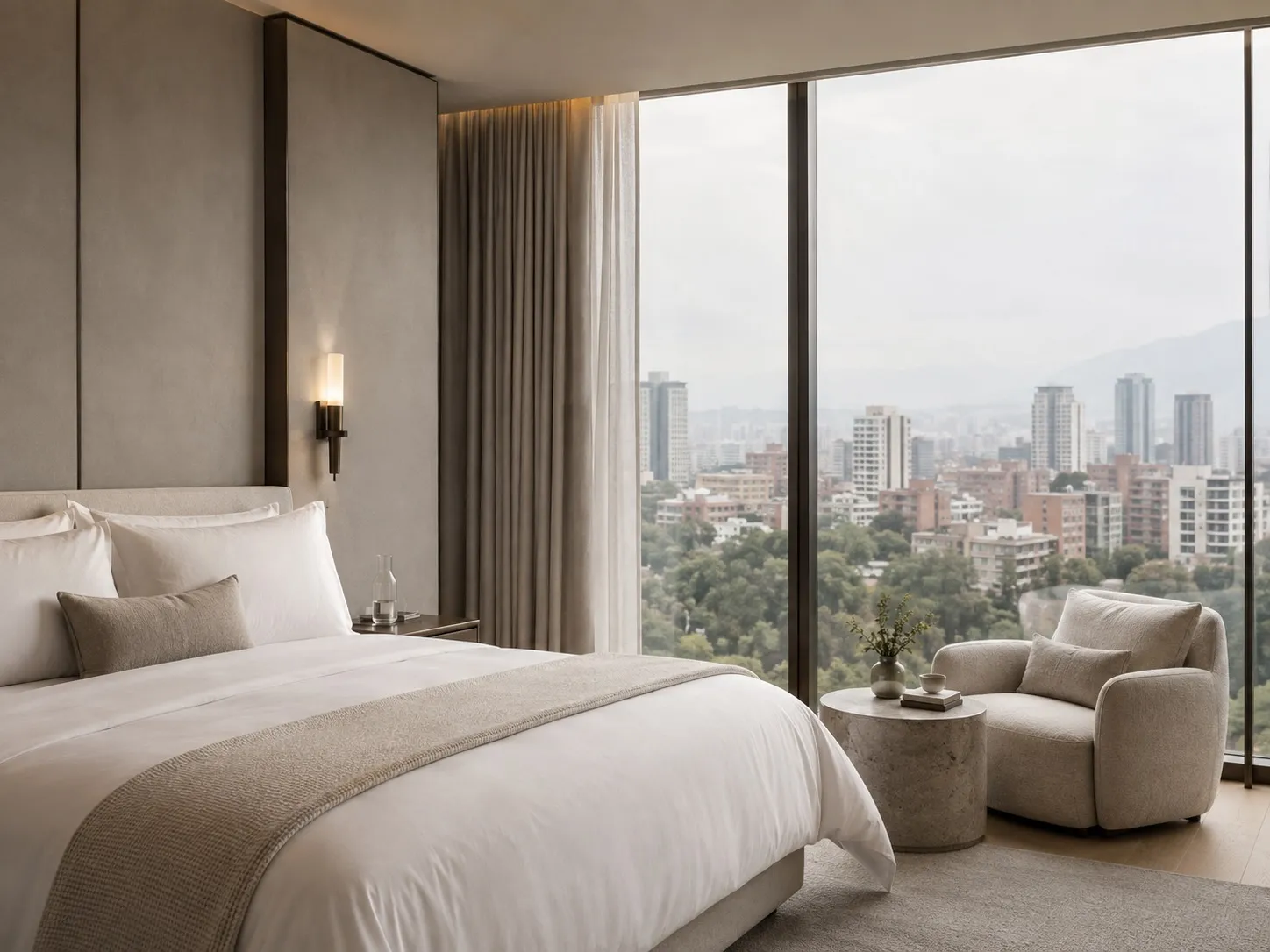 A quiet bedroom with soft daylight and a view across the city to the mountains