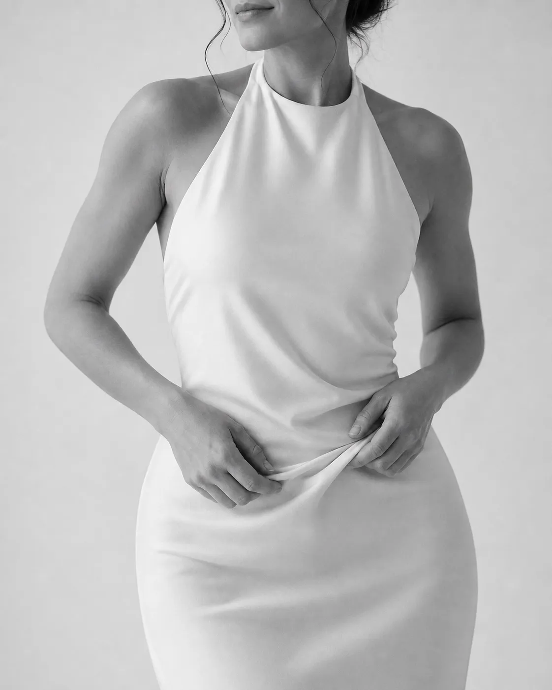 Black and white studio portrait of a woman in a white halter dress