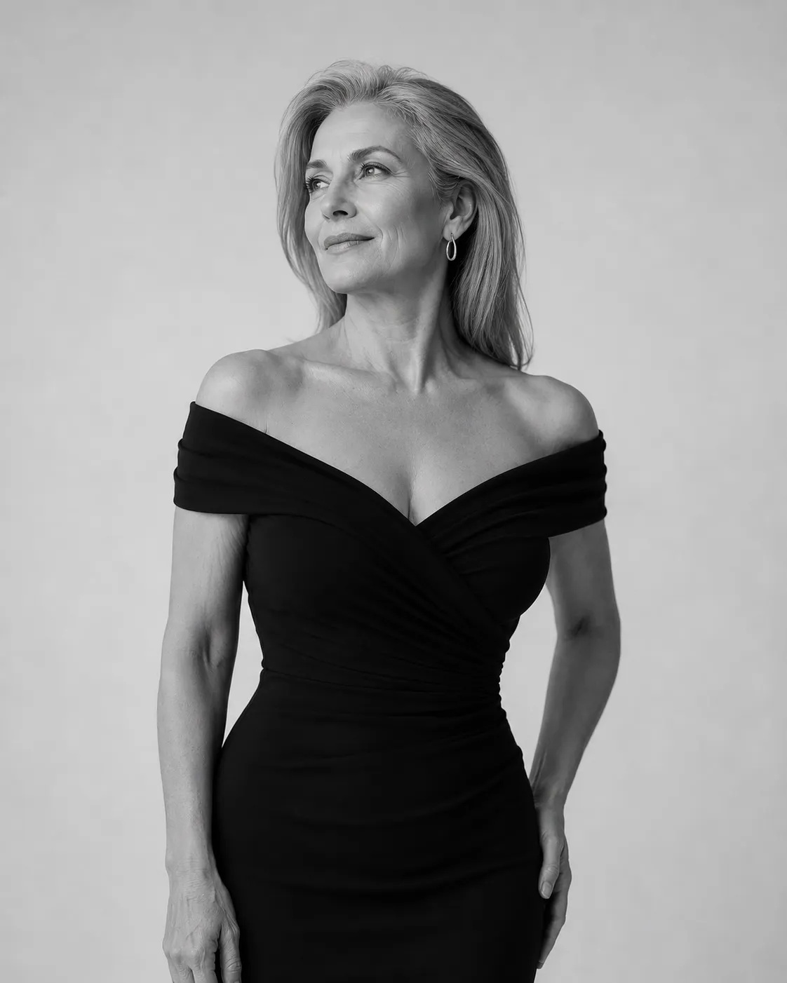 Black and white studio portrait of an older woman in a black off-shoulder dress