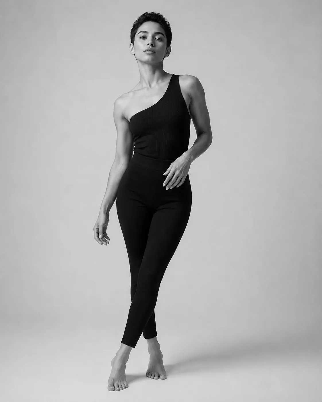 Black and white studio portrait of a woman in an asymmetric black bodysuit