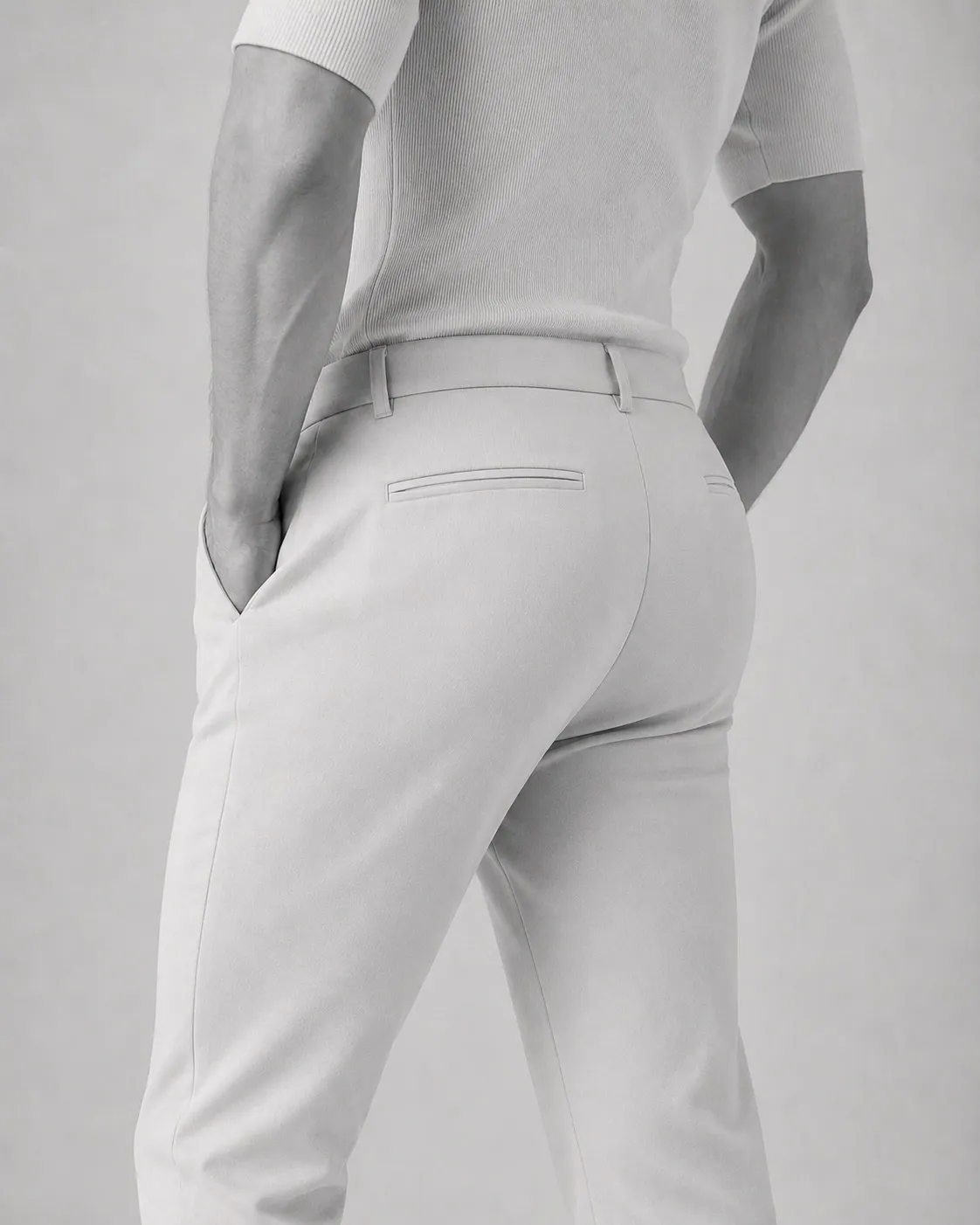 Black and white studio photograph of a figure in tailored white trousers