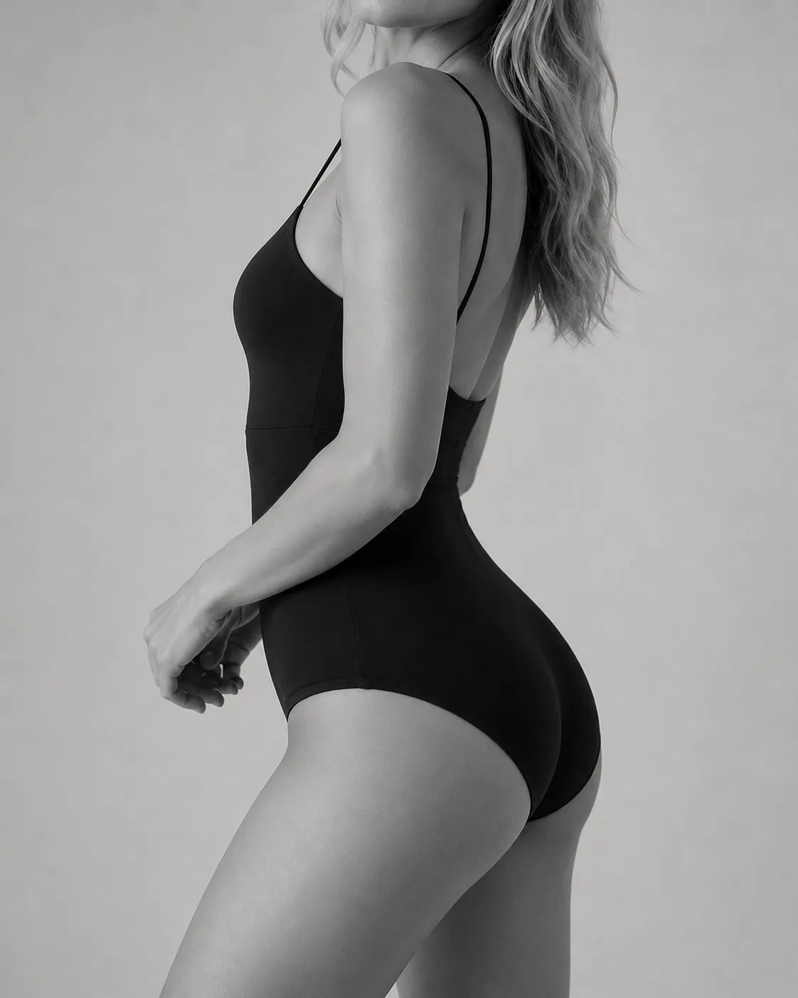 Black and white studio portrait of a woman in a black swimsuit, turned in profile