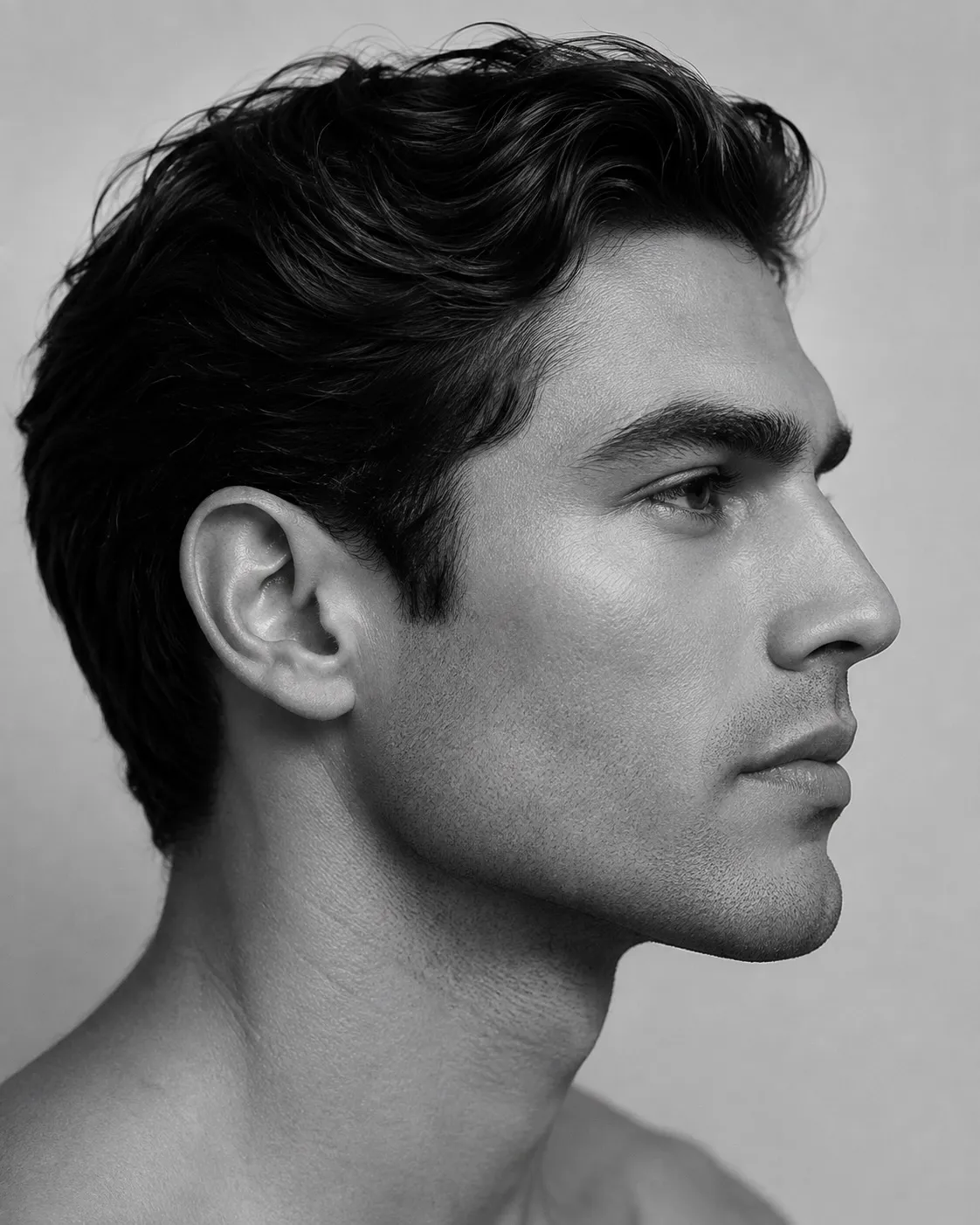 Black and white studio profile portrait of a man against a pale background