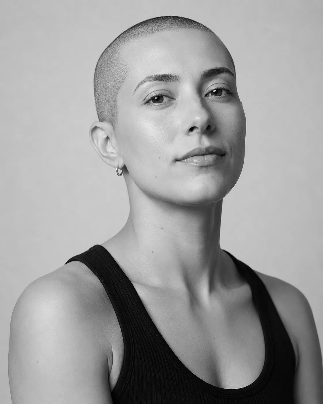Black and white studio portrait of a person looking directly at the camera